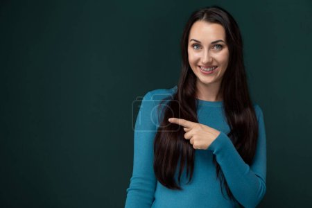 Eine Frau mit erhobenem Zeigefinger gestikuliert in Richtung eines unsichtbaren Objekts oder einer Richtung und lenkt die Aufmerksamkeit auf einen bestimmten Bereich. Ihre Körpersprache zeigt Konzentration und Dringlichkeit an, während sie das Ziel anzeigt.