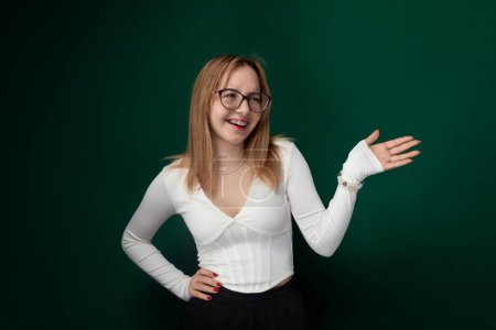 Une femme avec des lunettes porte une chemise blanche. Elle se tient devant un fond plat. L'accent est mis sur sa tenue et ses accessoires.