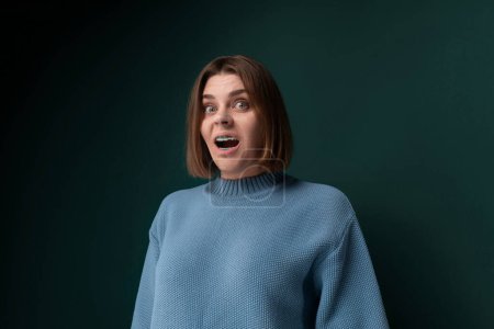 A woman with a surprised expression on her face, eyes wide open and mouth slightly agape. She appears to have just witnessed something unexpected or shocking.