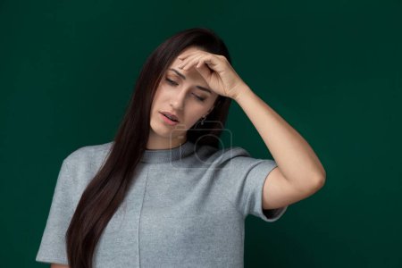 Una mujer angustiada sentada con la cabeza en las manos, mostrando sentimientos de abrumador o estrés. Ella aparece profundamente en el pensamiento, posiblemente tratando con agitación personal o emocional.