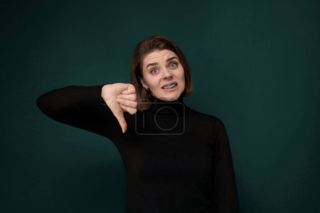Téléchargez les photos : Une femme contorse ludique son visage avec ses doigts, créant une expression comique. Elle tient son index et ses doigts du milieu près de ses yeux et de sa bouche, déformant ses traits dans un humour - en image libre de droit