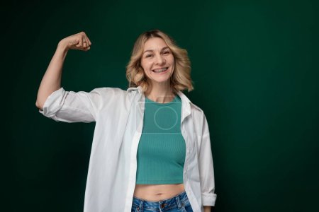Photo for A woman confidently poses for a picture with her fist raised in the air. She looks determined and empowered in the moment, showcasing strength and resilience. - Royalty Free Image