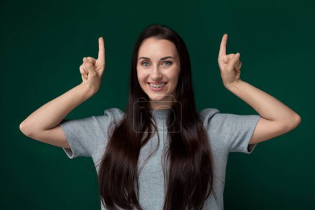 Une femme aux cheveux longs étend ses doigts pour créer un geste de paix. Ses cheveux coule autour d'elle comme elle sourit. Le fond est simple et concentré sur le geste des femmes.