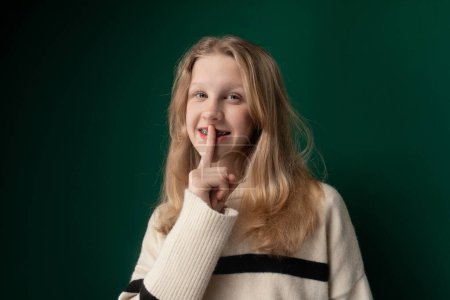 Une femme est représentée dans l'image faisant un geste de silence en plaçant son index sur ses lèvres. Son expression exprime une demande de tranquillité ou de secret.