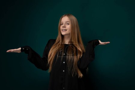 Photo for A woman wearing a black shirt is extending her hands outwards in front of her. Her palms are facing up. The background is simple and unobtrusive. - Royalty Free Image