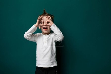 Photo for A young boy is seen with his hands covering his eyes. He appears to be shielding his eyes from something, possibly due to fear, surprise, or playfulness. His facial expression cannot be seen due to - Royalty Free Image