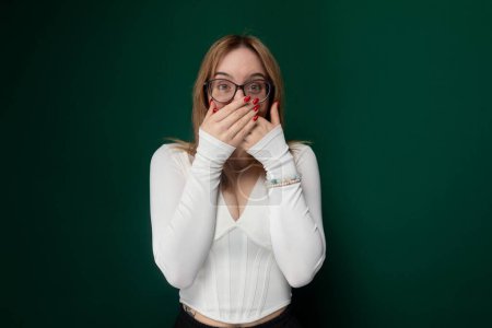 A woman is hiding her face by placing both hands over it, completely obscuring her features. She appears distressed, overwhelmed, or trying to shield herself from something.