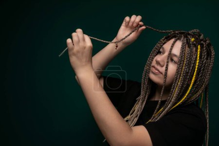 A woman with dreadlocks on her head is holding a pair of scissors, poised to cut hair. She appears focused on the task at hand, with determination in her eyes.