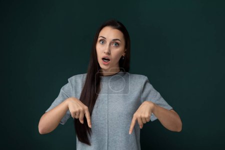 Photo for A woman with long hair is pointing at an object off-camera. Her hair cascades down her back as she gestures, drawing attention to her action. - Royalty Free Image