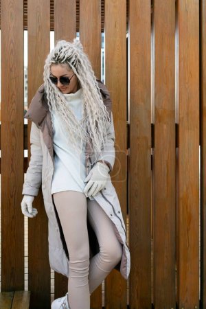 Une femme aux longs cheveux blancs est debout alors qu'elle porte un manteau de fourrure luxueux. Les cheveux de femmes cascades dans son dos comme elle pose élégamment dans la tenue chaude d'hiver.