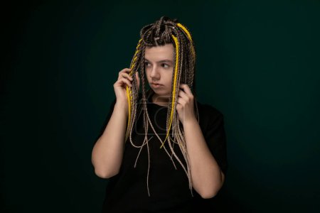 A woman with dreadlocks is seen holding her hair in front of her face. Her hands are gently gripping the tangled strands as they cascade down. The focus is on the intricate textures of her hair