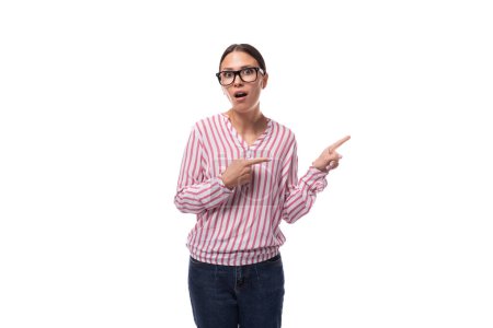 young joyful office worker woman dressed in a pink-white shirt points to an empty space.