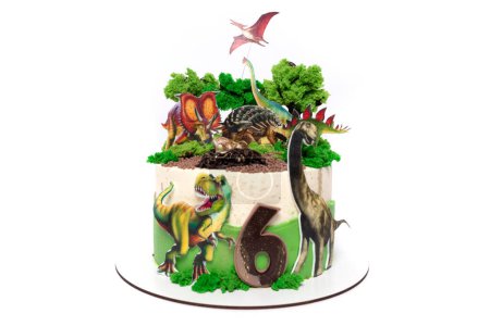 A birthday cake adorned with intricately designed edible dinosaurs and plants. The cake features a prehistoric theme with miniature dinosaur figures and lush greenery made of icing, creating a
