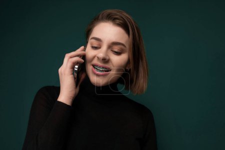 A woman is smiling while engaged in a conversation on her cell phone. She appears happy and animated as she communicates with someone over the phone.