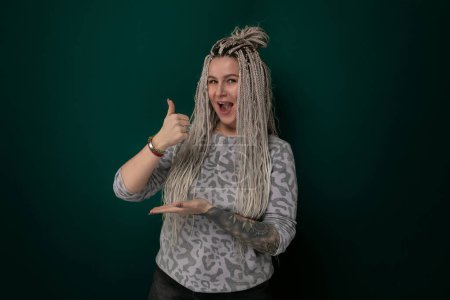 Photo for A woman with dreadlocks is smiling and giving a thumbs up gesture. Her dreadlocks are styled in a neat and tidy manner. She appears confident and positive in her expression. - Royalty Free Image