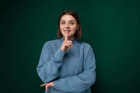 Foto de Una mujer que lleva un suéter azul señala directamente a la cámara con un gesto confiado. Ella parece decidida y enfocada en transmitir un mensaje o enfatizar un punto. - Imagen libre de derechos