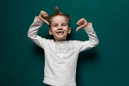 Photo for A young boy is standing with his hands raised in the air. He looks excited and energetic, with a big smile on his face as he expresses joy and exuberance. - Royalty Free Image