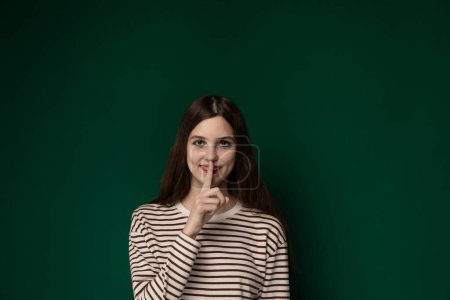 Eine Frau posiert für ein Foto, wobei ihr ein Finger zart in den Mund gelegt wird. Sie wirkt selbstbewusst und selbstbewusst in ihrer Pose.