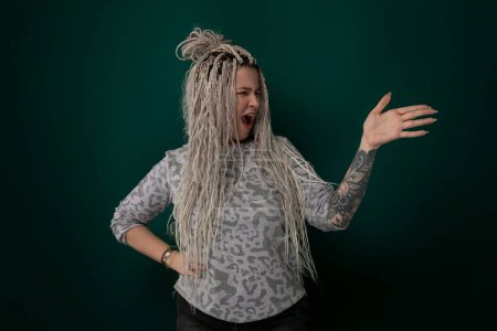 A woman with dreadlocks is contorting her facial expression, possibly showing disgust or amusement. Her distinctive hairstyle frames her face as she gestures, creating a visually striking moment.
