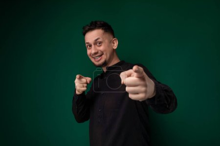 Un hombre que lleva una camisa negra está dando con entusiasmo un gesto de pulgar hacia arriba, mostrando aprobación o acuerdo. Parece positivo y confiado en su acción.