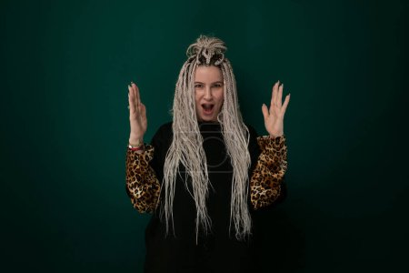 A woman with long white hair is standing confidently, wearing a stylish leopard print jacket. Her striking appearance is enhanced by the contrast between her hair and the bold jacket pattern.