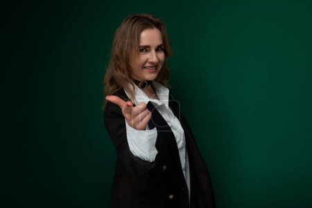 Photo for A woman dressed in a suit is standing in a confident posture, pointing directly at the camera with a serious expression on her face. She exudes authority and assertiveness in this corporate setting. - Royalty Free Image
