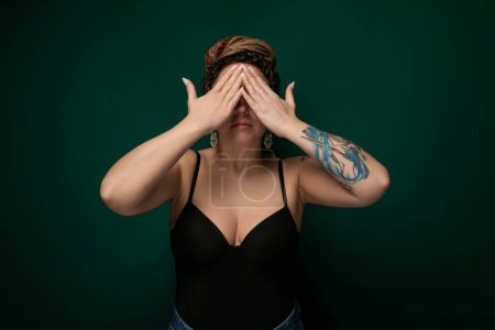 A woman sitting with her hands covering her eyes in a gesture of blocking out light or shielding herself from a bright or overwhelming situation. She appears to be seeking privacy or taking a moment