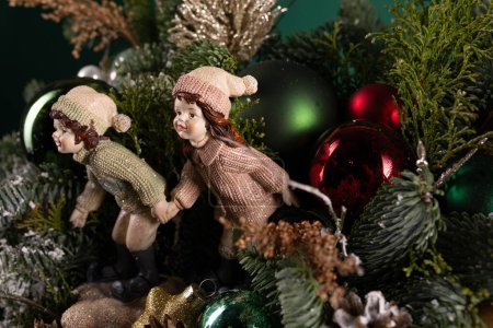 Deux figurines sont placées au sommet d'un sapin de Noël festif. Les figurines ajoutent une touche décorative à l'arbre, mettant en valeur le thème des vacances.