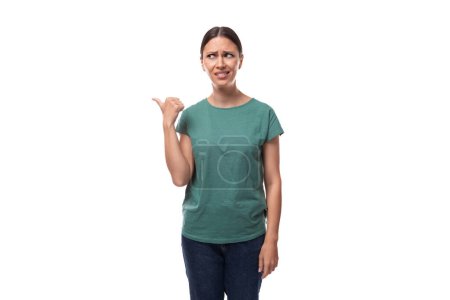 Foto de Bonita joven morena mujer en camiseta verde tiene dudas y mira hacia otro lado. - Imagen libre de derechos