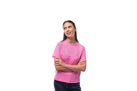 Foto de Joven delgada mujer morena caucásica en una camiseta rosa sobre un fondo blanco con espacio para copiar. - Imagen libre de derechos