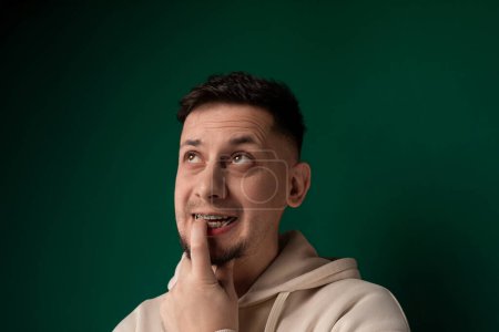 Ein Mann verzerrt sein Gesicht auf komische Weise, indem er seinen Finger benutzt, um seine Gesichtszüge zu manipulieren, wodurch ein humorvoller Ausdruck entsteht.