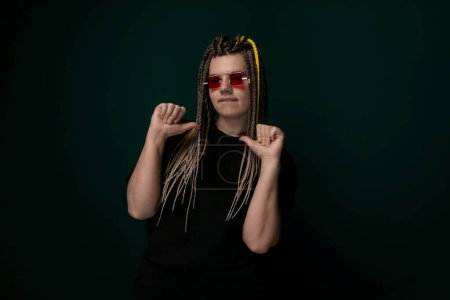 A woman with dreadlocks wearing red sunglasses is featured in this photo. She exudes confidence as she poses for the camera, showcasing her unique style and personality.