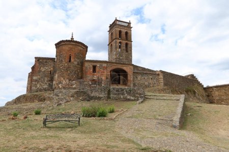Photo for Almonaster la Real, Huelva, Spain, June 21, 2023: 13th century Romanesque apse, entrance door and minaret of the 10th century mosque of Almonaster la Real. Huelva, Spain - Royalty Free Image