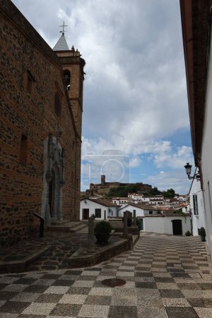 Photo for Almonaster la Real, Huelva, Spain, June 21, 2023: Vertical view. Puerta del Perdon of the church of San Martin with the mosque in the background in Almonaster la Real, Huelva, Spain - Royalty Free Image