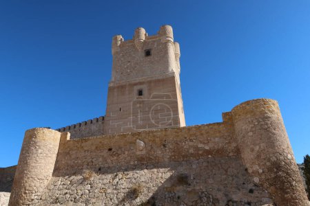 Villena, Alicante, Spain, March 6, 2024: Tower and stone defensive wall of the medieval castle of Arab origin of Atalaya. Villena, Alicante, Spain