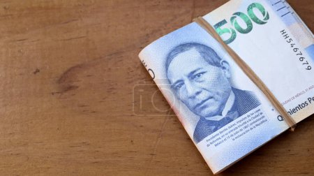 Téléchargez les photos : Mexican banknotes tied with a rubber band on a wooden table - en image libre de droit