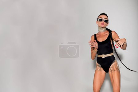 Photo for Stunning model with a slender build and captivating long hair, radiating confidence in sleek black lingerie against a warm studio backdrop - Royalty Free Image