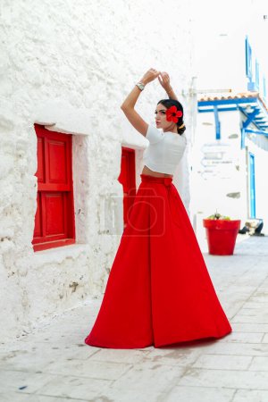 Téléchargez les photos : Attrait des vacances : Une femme brune en robe d'été rouge respire le style dans un contexte de villas grecques, incarnant l'humeur du voyage - en image libre de droit