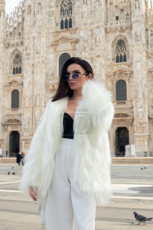 Téléchargez les photos : Promenade dans la ville : Une jeune femme heureuse profite des sites touristiques de Milan, souriant devant l'emblématique cathédrale de Milan, symbolisant l'amour pour l'exploration - en image libre de droit