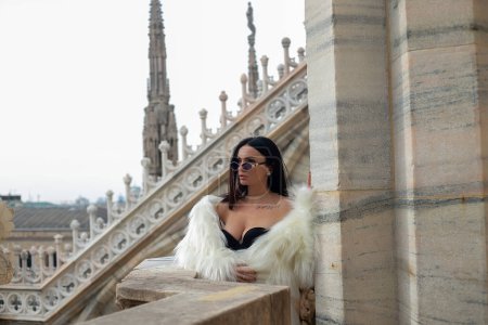 Téléchargez les photos : Milan vista : Une belle touriste prend la vue depuis le toit de la cathédrale de Milan, son manteau de fourrure blanc ajoutant une touche de glamour à la scène - en image libre de droit