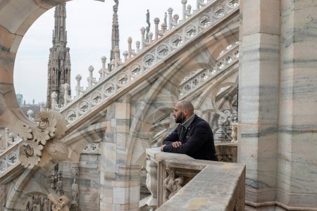 Photo for Travel, holidays and winter vacations concept - Milan adventure: A carefree young man embraces Milan's beauty from above, his smile reflecting the joy of exploration on the roof of Milan Cathedral - Royalty Free Image