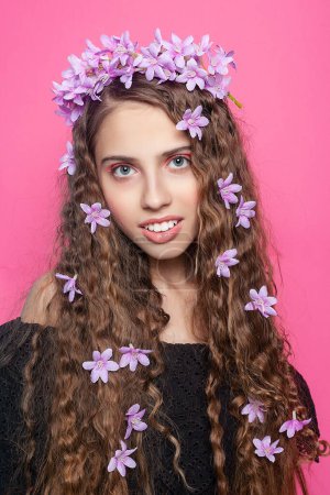 Lockiges Mädchen mit der subtilen Schönheit lila Blüten, verkörpert ein Gefühl von Verzauberung und ätherischem Charme
