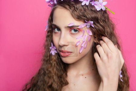 Téléchargez les photos : Beauté aux cheveux bouclés orné de fleurs violettes dans ses cheveux, rayonnant d'élégance et de charme dans un arrangement floral fantaisiste - en image libre de droit