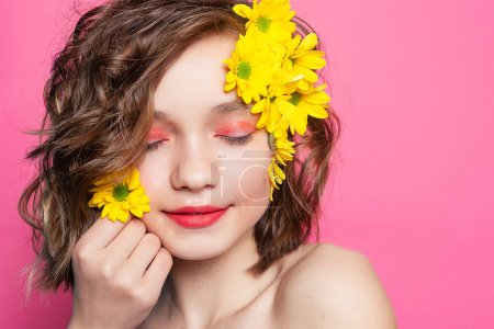 Foto de Imagen cautivadora de una joven con una sonrisa radiante, sosteniendo una vibrante flor amarilla sobre un suave telón de fondo rosa. Perfecto para el branding femenino y citas inspiradoras. - Imagen libre de derechos