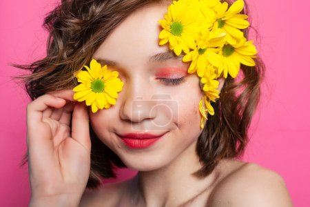 Foto de Delicada fotografía de una joven sosteniendo tiernamente una flor amarilla, su rostro parcialmente oscurecido sobre un fondo rosado rubor. Perfecto para expresar fragilidad y sensibilidad. - Imagen libre de derechos