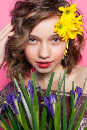 Photo for Captivating image of a young lady immersed in nature, her face partially hidden by a dainty yellow bloom against a soft pink backdrop. Ideal for expressing beauty and grace. - Royalty Free Image