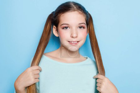 Photo for Quirky and charming, this little girl brings laughter and joy with her silly expressions, creating a delightful portrait against a blue backdrop. - Royalty Free Image