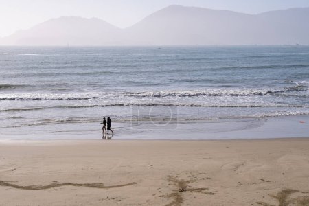 Foto de Un par de amigos caminando en la playa de arena al amanecer en vacaciones de primavera en un destino soleado y paradisíaco. Concepto de vacaciones de viaje. Lerici, Liguria, Italia - Imagen libre de derechos