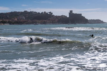 Foto de Los jóvenes surfistas atléticos montan la ola con salpicaduras. Lugar de surf de escapadas en Lerici, Liguria, Italia - Imagen libre de derechos