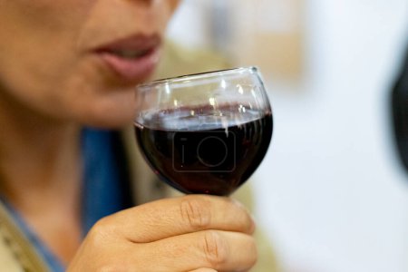 Foto de Vino. Momento justo donde una mujer bebe una copa de vino tinto. Fotografía horizontal. - Imagen libre de derechos